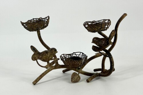 Rusty metal sculpture of birds perched on curved branches with woven wire nests.