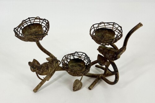 Rusty metal sculpture featuring three wire basket-like flower heads on curved stems against a white background