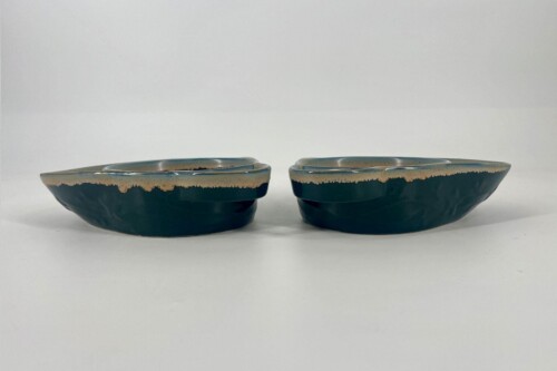 Pair of dark teal glazed ceramic bowls with a beige rim, placed side by side on a white surface.
