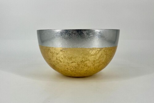 Decorative bowl with a silver upper half and a gold-leaf textured lower half on a white surface