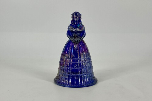 Blue glass figurine of a woman in a long, patterned dress, hands clasped in front. Decorative sculpture.