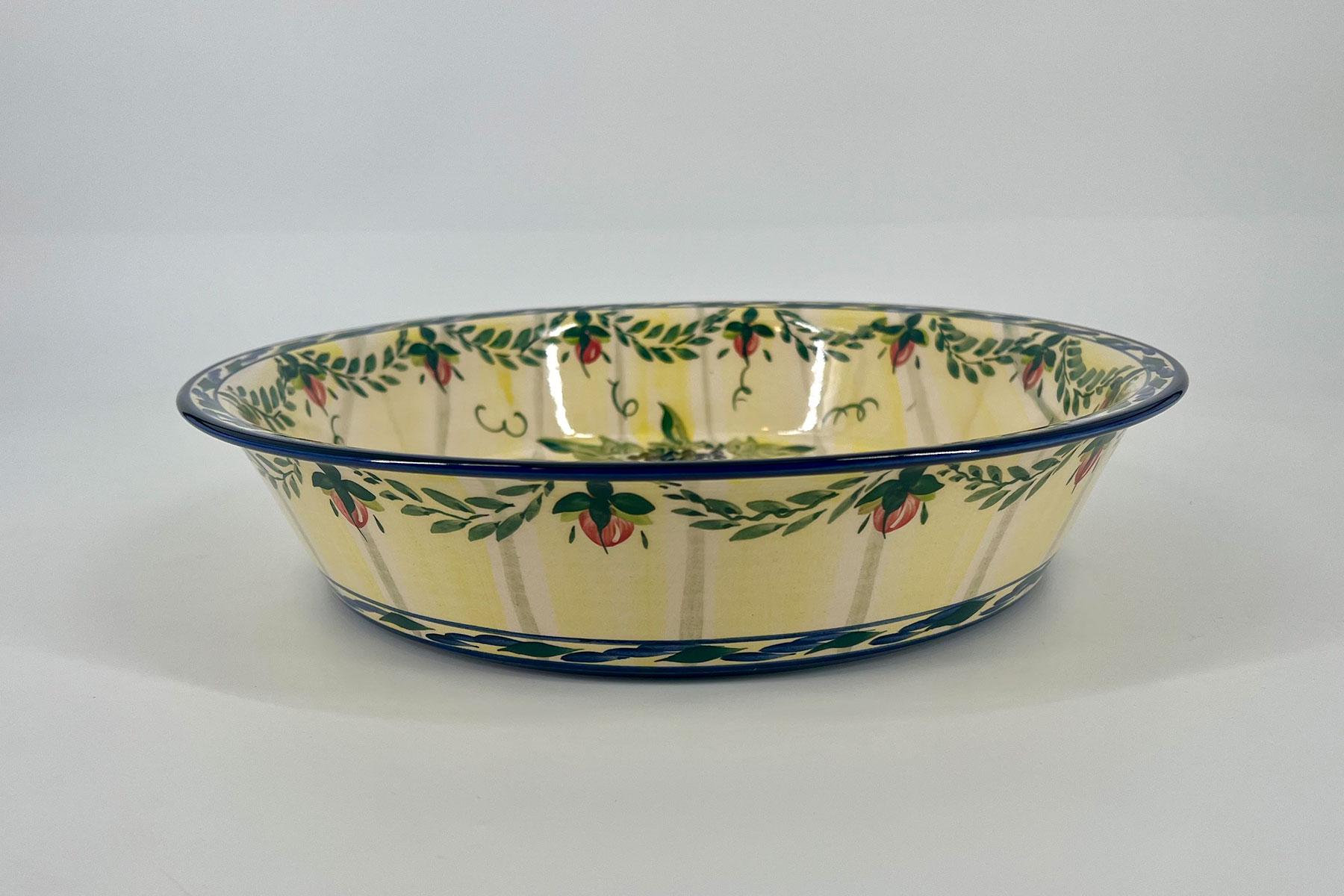 Decorative ceramic bowl with yellow glaze and a blue rim, featuring a green olive-leaf pattern around the rim.