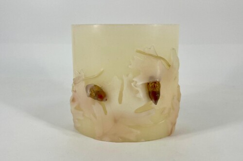 Cream-colored bar (possibly soap) with rough, sculpted edges and two brown seed-like objects embedded on the front.