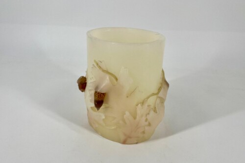 Cream-colored pillar candle with a raised oak-leaf wreath and acorn accents at the base, decorative woodland design