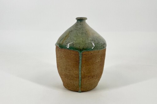Rustic ceramic vase with a green-glazed, conical top and brown textured body with a visible glaze drip down the edge.