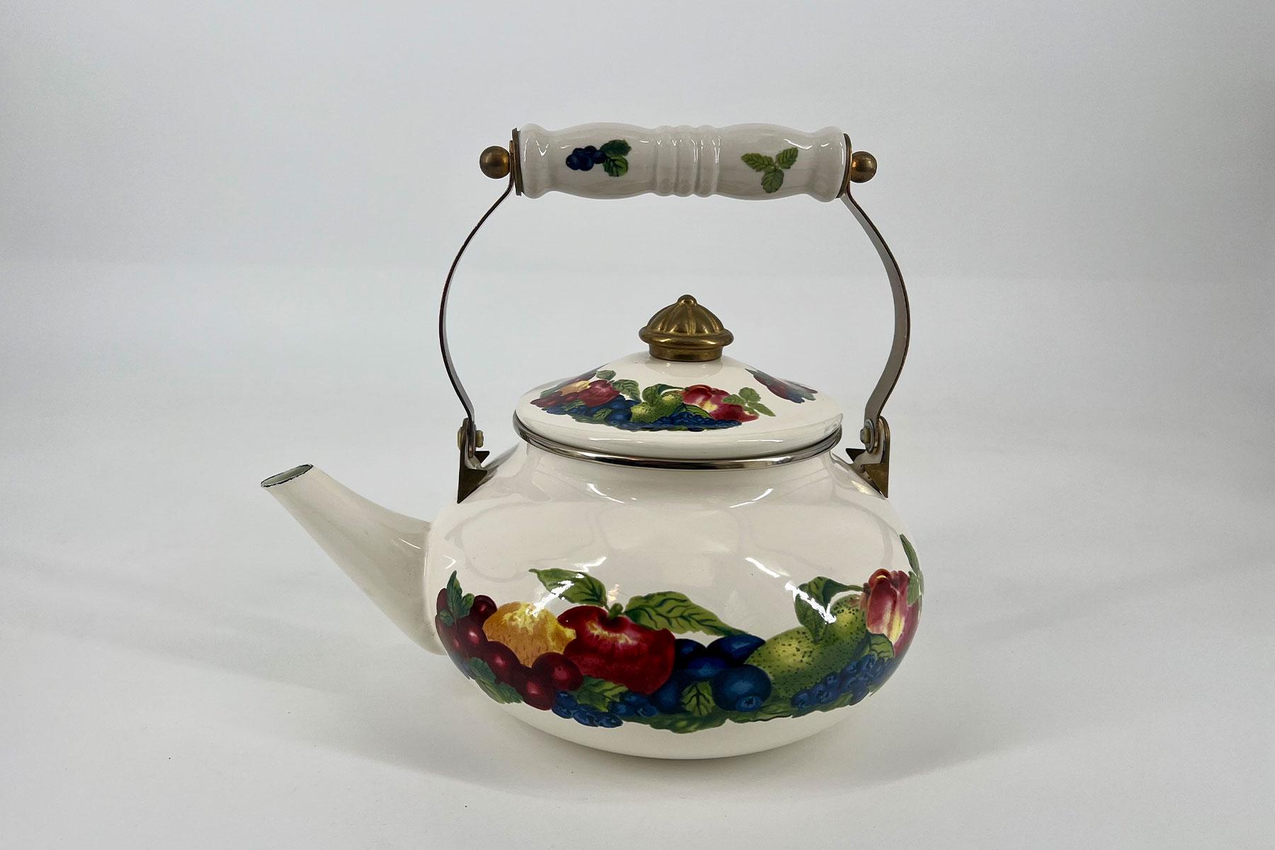 White porcelain teapot with a brass handle and lid, decorated with a colorful grape and fruit pattern.