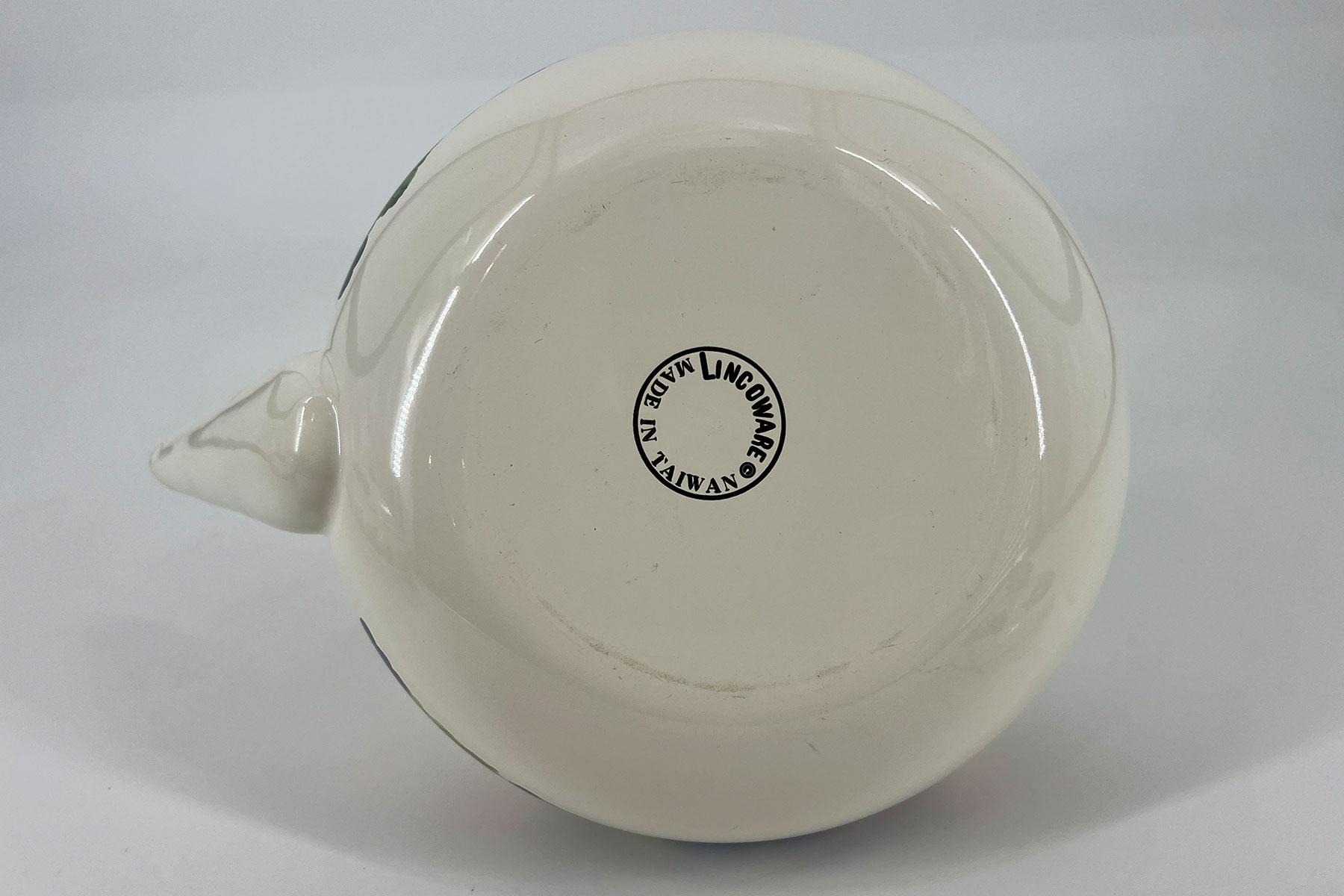 White ceramic teapot viewed from its bottom, with the spout on the left and a circular 'Made in Taiwan' stamp on the base on a white surface.