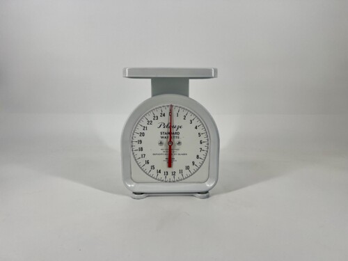 White vintage kitchen scale with a round dial and a flat top platform, showing weight indicators around the edge.
