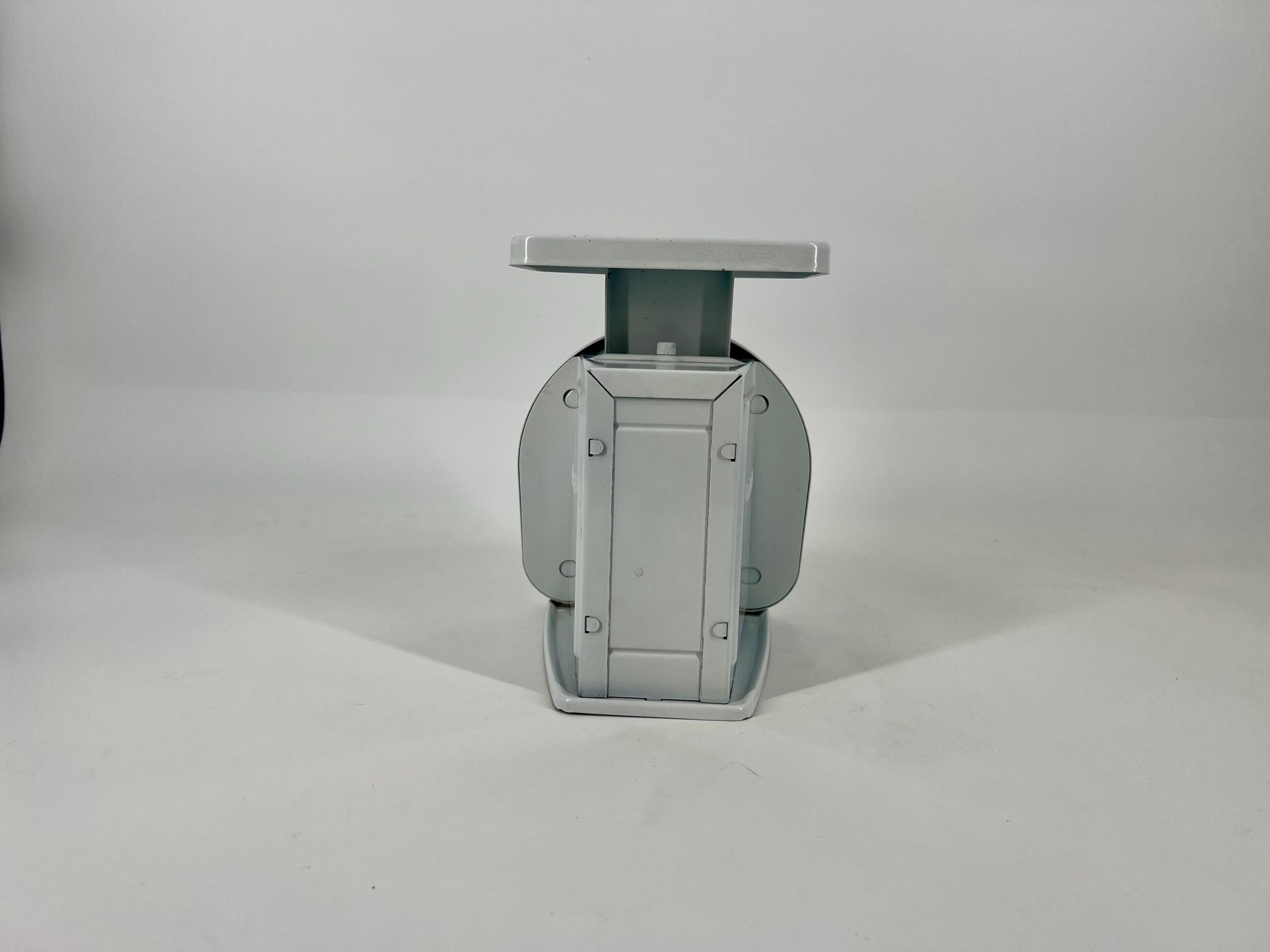 Close-up of a gray metal mounting bracket with a rectangular cap against a plain light-gray background.