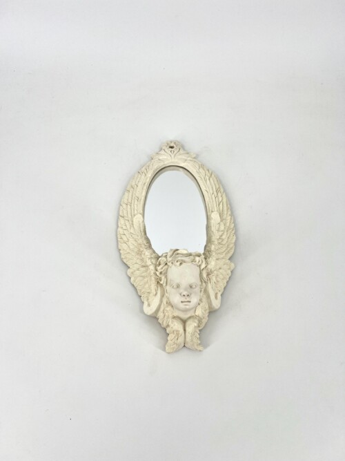 Oval antique-style wall mirror with a sculpted cherub face and feathered wings forming the frame.