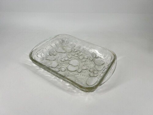 Square glass dish filled with coins, photographed at a tilted angle.
