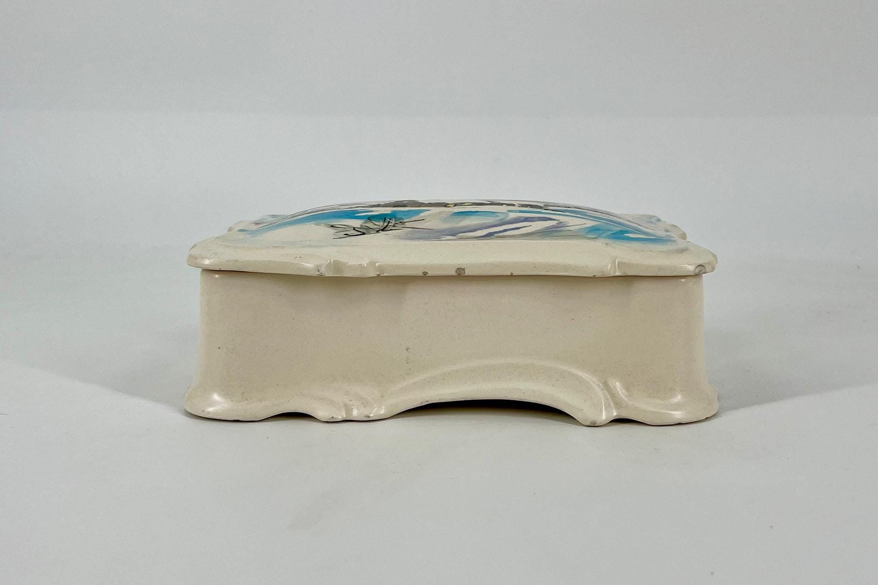 Cream ceramic tissue box cover with a hinged, decorative lid featuring blue and black brushstroke design