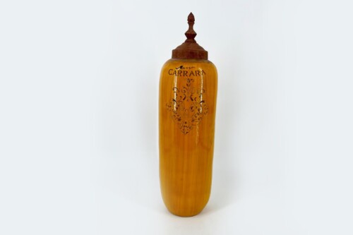 Tall amber glass bottle with an ornate rust-colored metal lid and decorative scrollwork on the front.