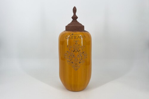 Amber glass apothecary bottle with an ornate metal stopper and decorative engraving on the front panel