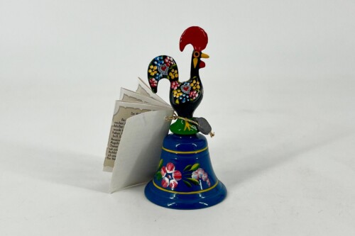 Colorful ceramic rooster figurine with a floral pattern on a blue pedestal, standing beside folded papers.
