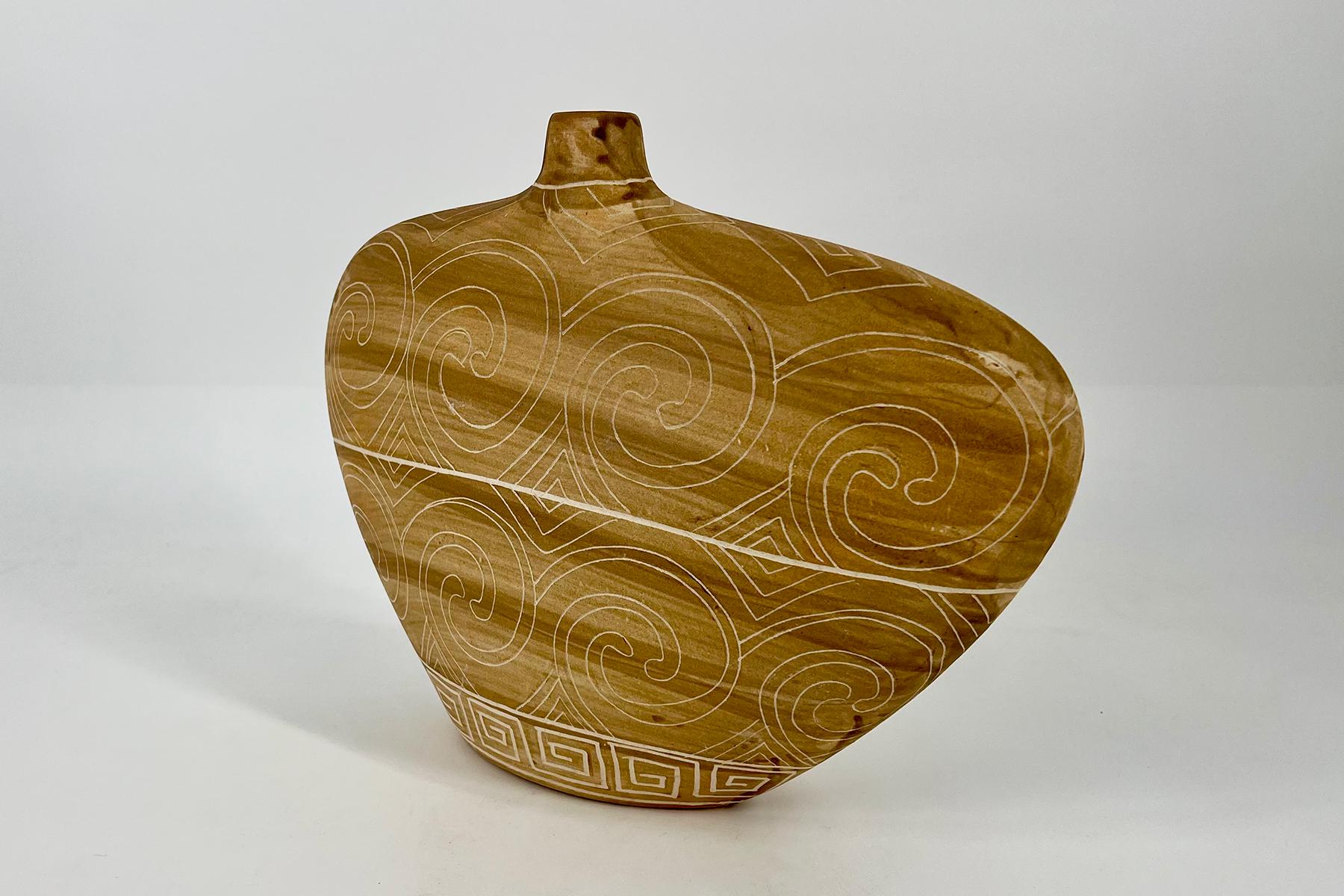 Brown ceramic vase with white carved swirl patterns and a geometric band near the base, set against a plain white background.
