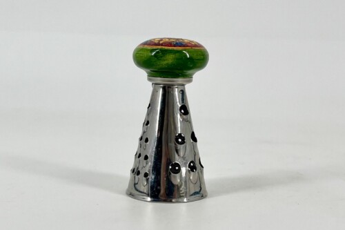 Close-up of a champagne cork with a round green seal atop a silver perforated foil neck.