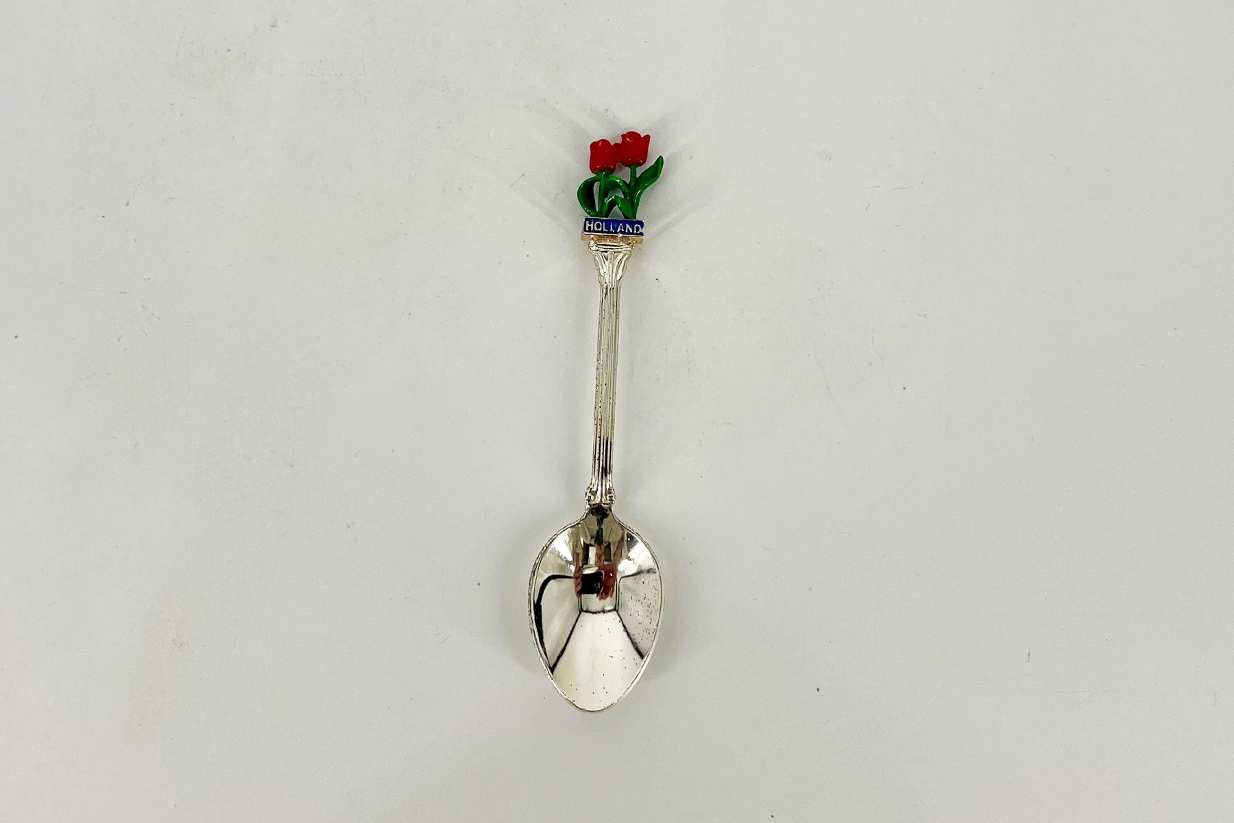 Decorative souvenir spoon with a red tulip bouquet and a blue 'Holland' band on the handle.