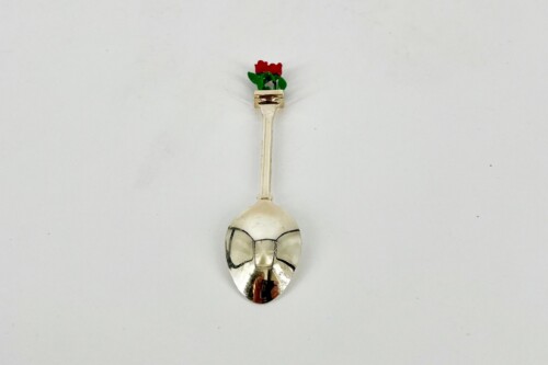 Silver spoon with a skull-shaped bowl and a small red rose blooming at the top of the handle.