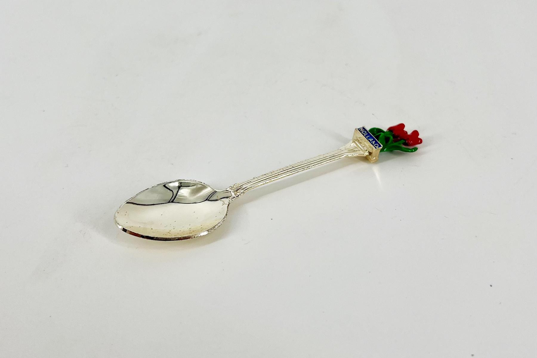 Decorative silver spoon with a handle shaped like a bouquet of red roses at the end.