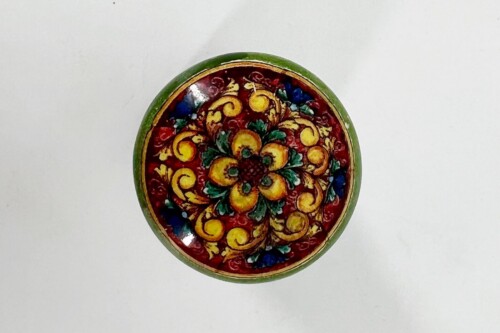 Round green lacquered box lid with an intricate red floral interior and yellow flowers in a dense pattern.