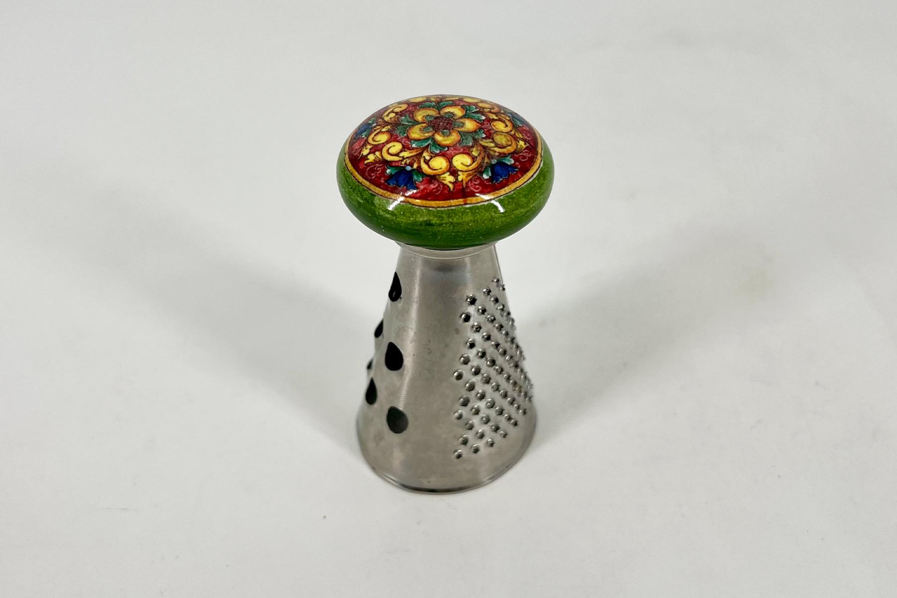 Colorful round decorative knob with floral pattern atop a perforated metal shaker base.