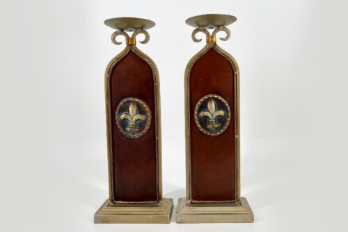 Pair of antique candle holders with gold frames, brown leather panels, and fleur-de-lis medallions on square bases.