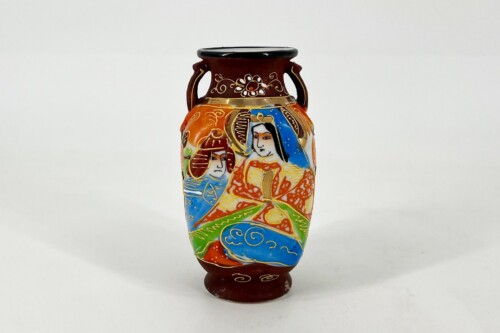 Colorful ceramic vase with two handles and a hand-painted scene of two people in traditional dress, surrounded by swirling patterns on a vibrant orange, blue, and green surface.