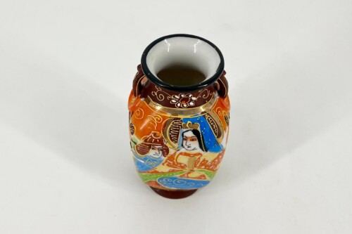 Colorful ceramic vase with painted folk figures and floral patterns, viewed from above on a white background.