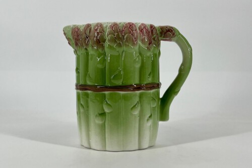 Green cactus-shaped ceramic mug with a ribbed surface and a curved handle on the right; the top edge has red-tinted, bud-like clusters resembling cactus blossoms.