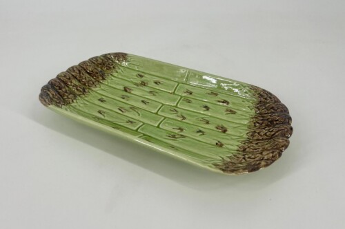 Oval ceramic serving platter with green glaze and brown mottled edges, ribbed leaf-like pattern.
