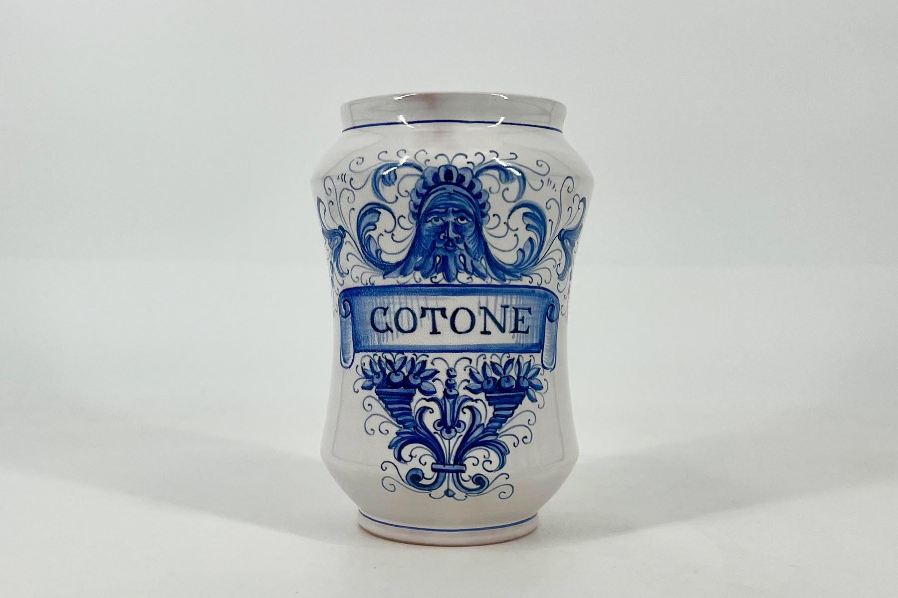 White ceramic vase with cobalt blue decorative patterns and a blue ribbon banner reading COTONE