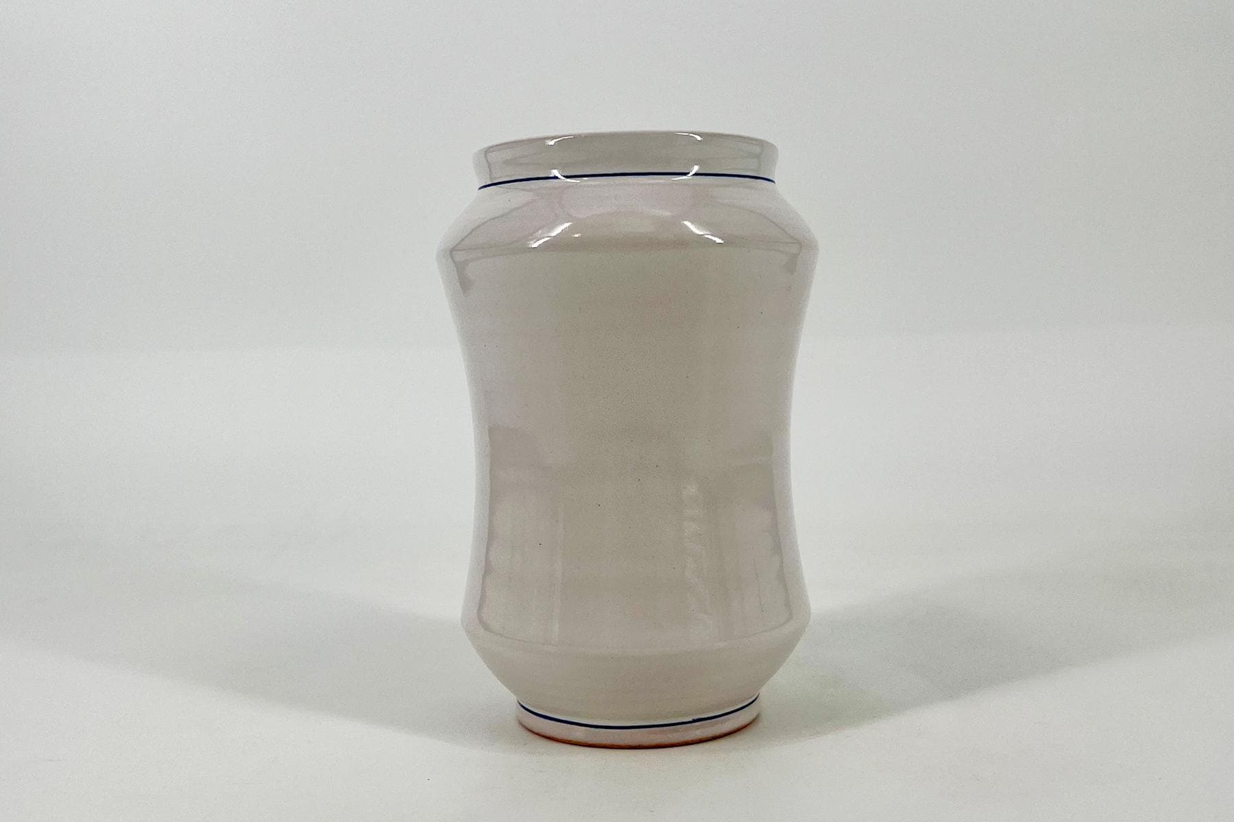 White ceramic bottle with a narrow neck and a thin blue line near the rim on a white background