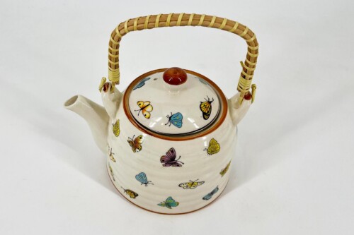 Cream-colored ceramic teapot with colorful butterfly patterns and a woven bamboo handle and lid knob.