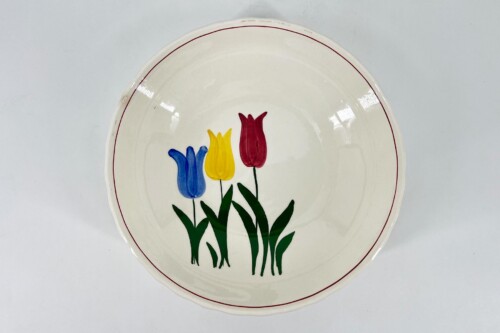 White ceramic plate decorated with blue, yellow, and red tulips and green stems in the center.