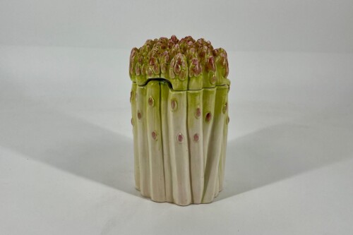 Ceramic sculpture of tightly bound white-green asparagus stalks with purple-tinted tips on top.