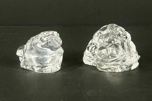 Two clear glass sculptures resembling jagged rocks on a black surface.