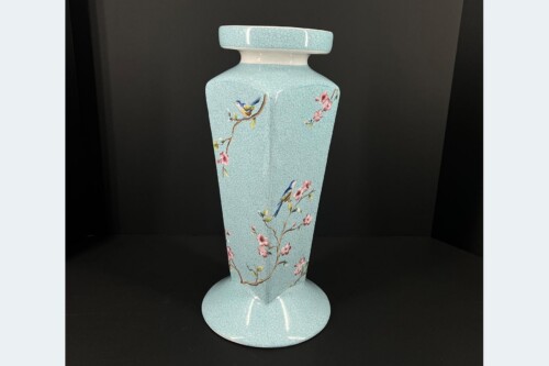 Tall light blue porcelain vase with crackled glaze and floral branches featuring pink blossoms and small blue birds on a dark background.