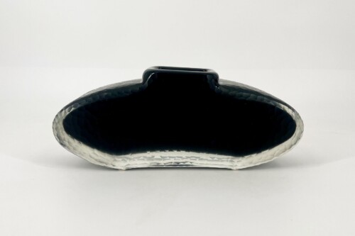 Glossy black oval glass sculpture with a hammered silver base on a white background.