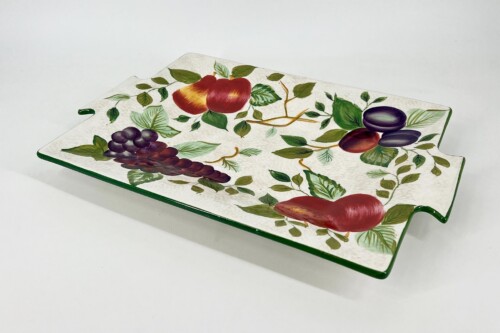 Decorative ceramic tray with fruit and foliage pattern (apples, grapes, plums) along a green edge.