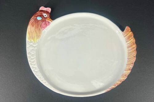 White ceramic plate with a turkey head at the left edge and a textured tail on the right.