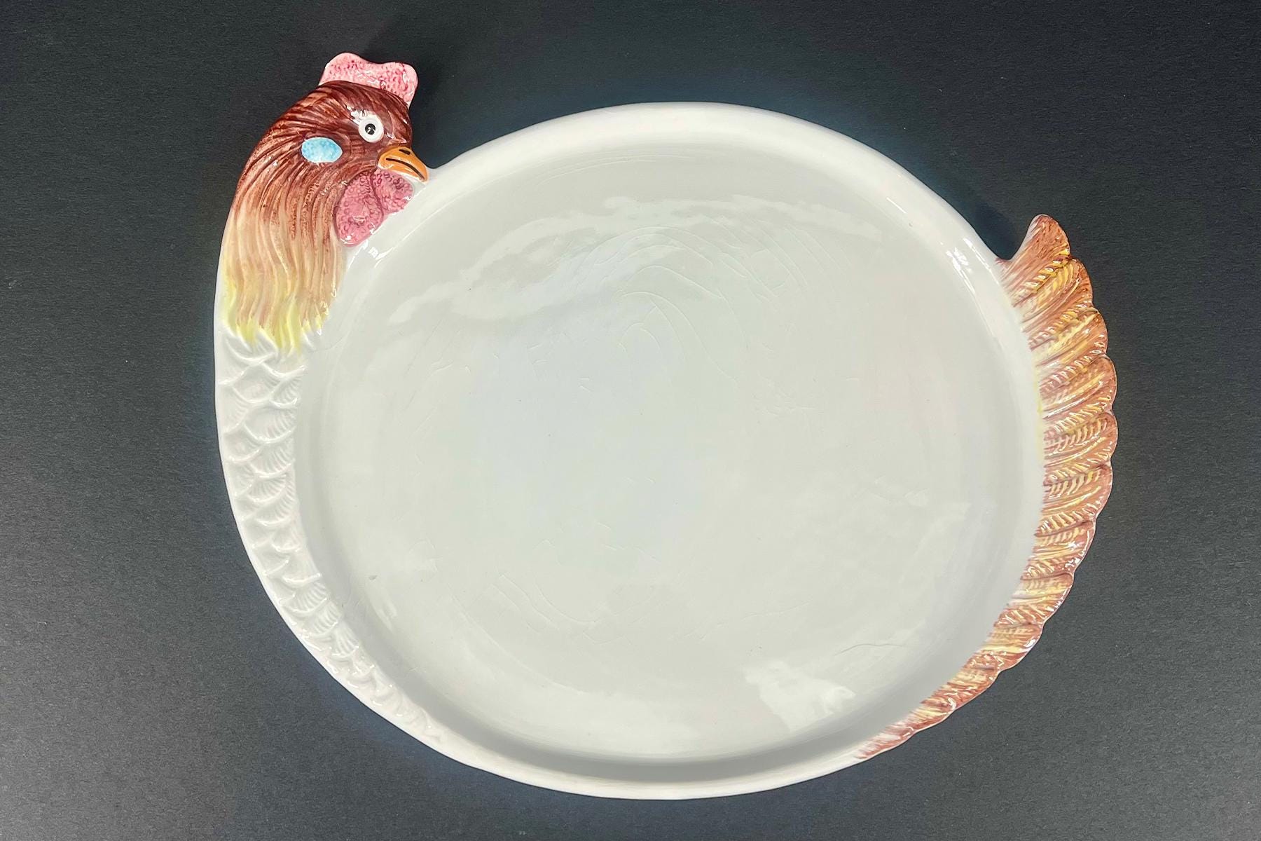 White ceramic plate with a turkey head at the left edge and a textured tail on the right.
