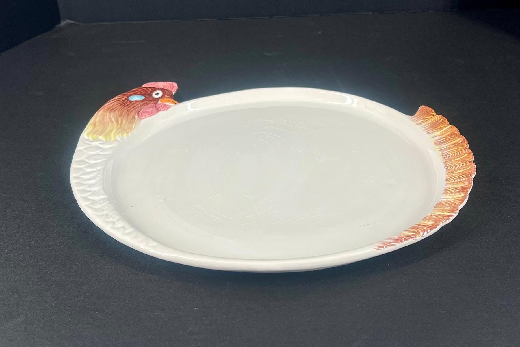 Decorative white ceramic serving platter shaped like a turkey, with a turkey head at one end and feathered rim on the opposite edge.