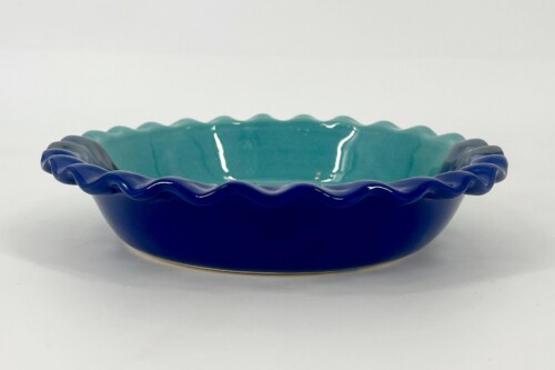 Blue glass bowl with a ruffled teal interior on a white background