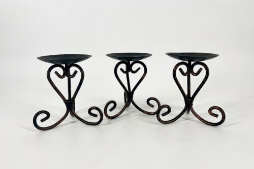 Three-candle holder with black wrought-iron scrolls and heart-shaped accents on a white background.