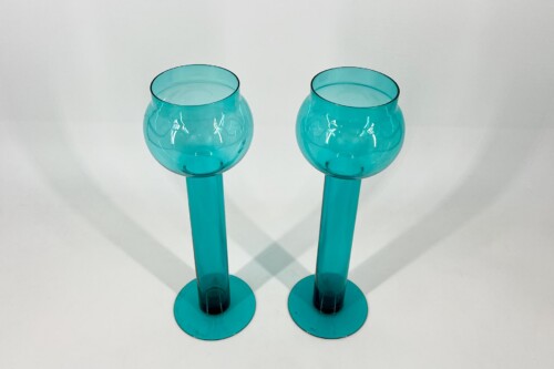 Two turquoise glass goblets on a white background, placed side by side with rounded bowls and tall stems.
