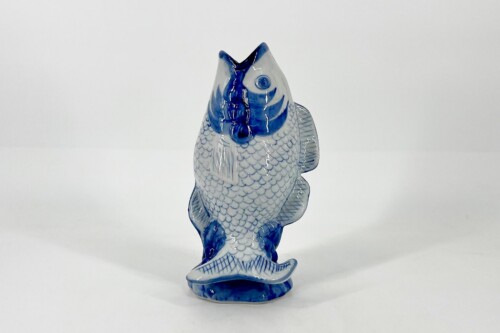Blue-and-white porcelain fish sculpture on a small pedestal against a white background, a decorative figurine for display.