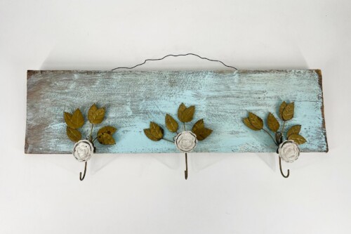 Rustic blue distressed wooden shelf with three decorative white ceramic flowers and gold-painted leaves on metal hooks.