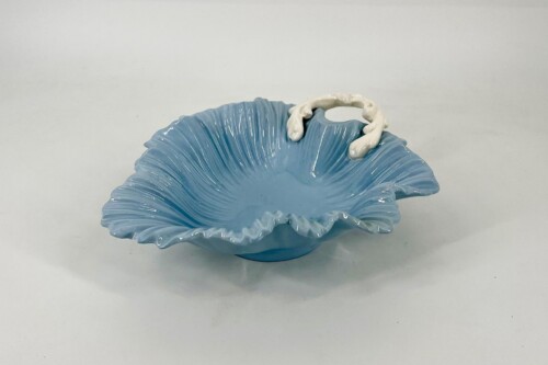 Blue ruffled-edge bowl with white loop handles on a white background, decorative tableware.