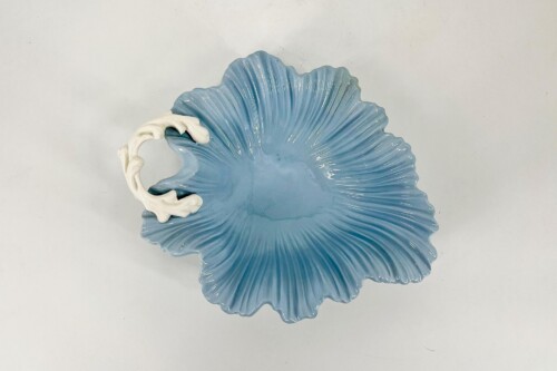 Blue, shell-shaped ceramic dish with a white decorative handle along the rim.